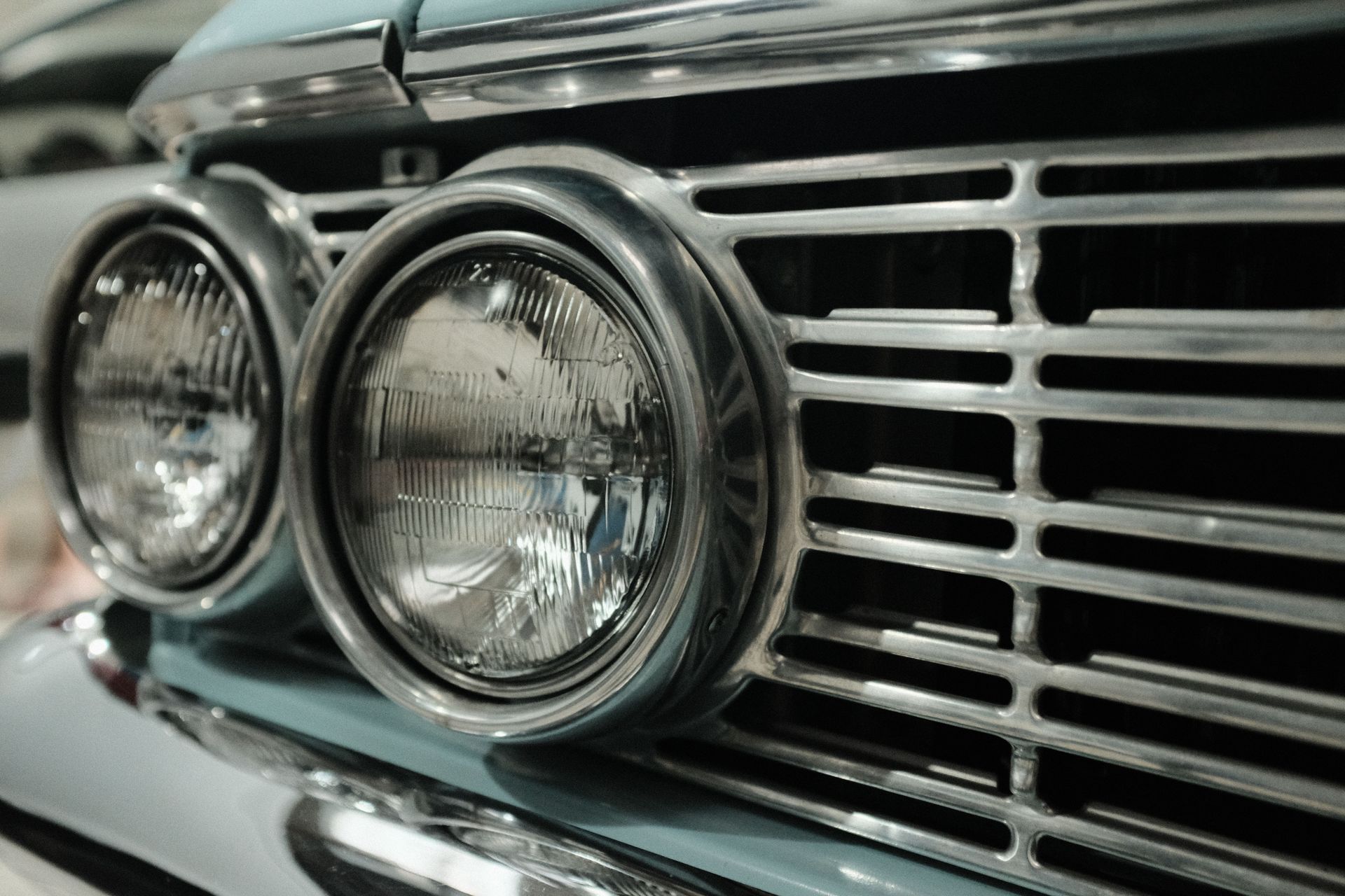 Detailed view of classic car headlights and metallic grill, showcasing vintage automotive design.